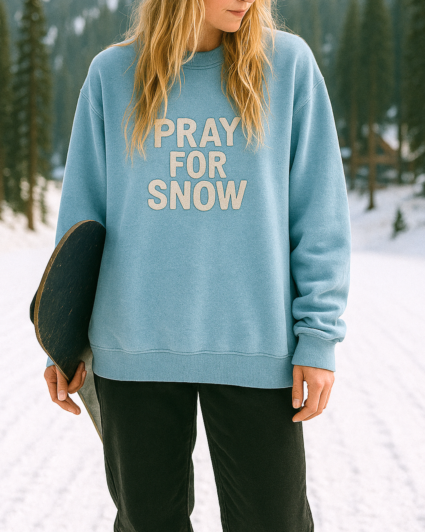 Snowboarder wearing oversized ‘Pray For Snow’ sweatshirt at snowy mountain resort, winter graphic crewneck